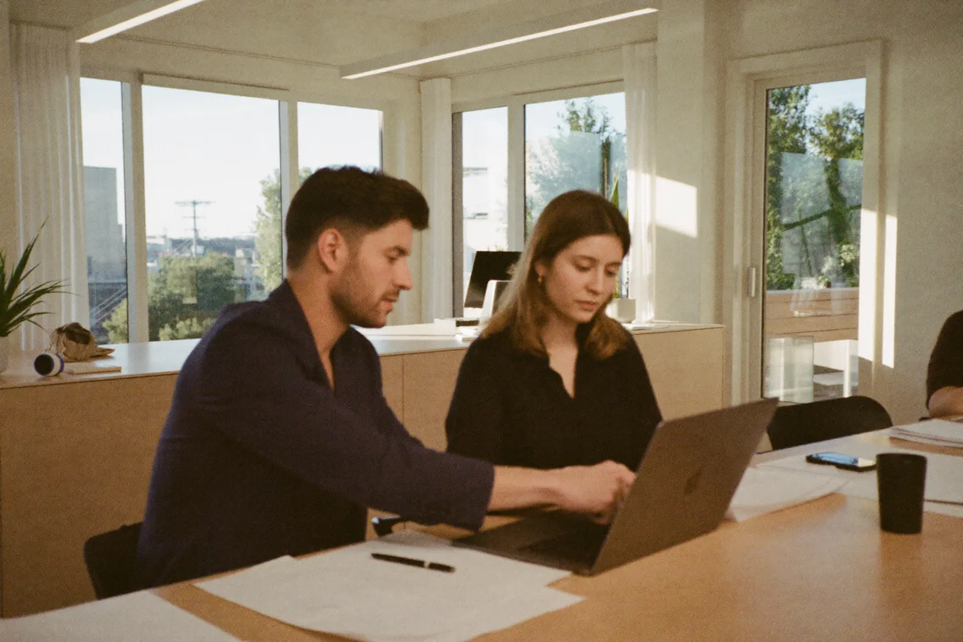 Zwei Menschen besprechen am Tisch eine Kalkulation am Laptop